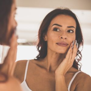 Woman with dark hair touching her face