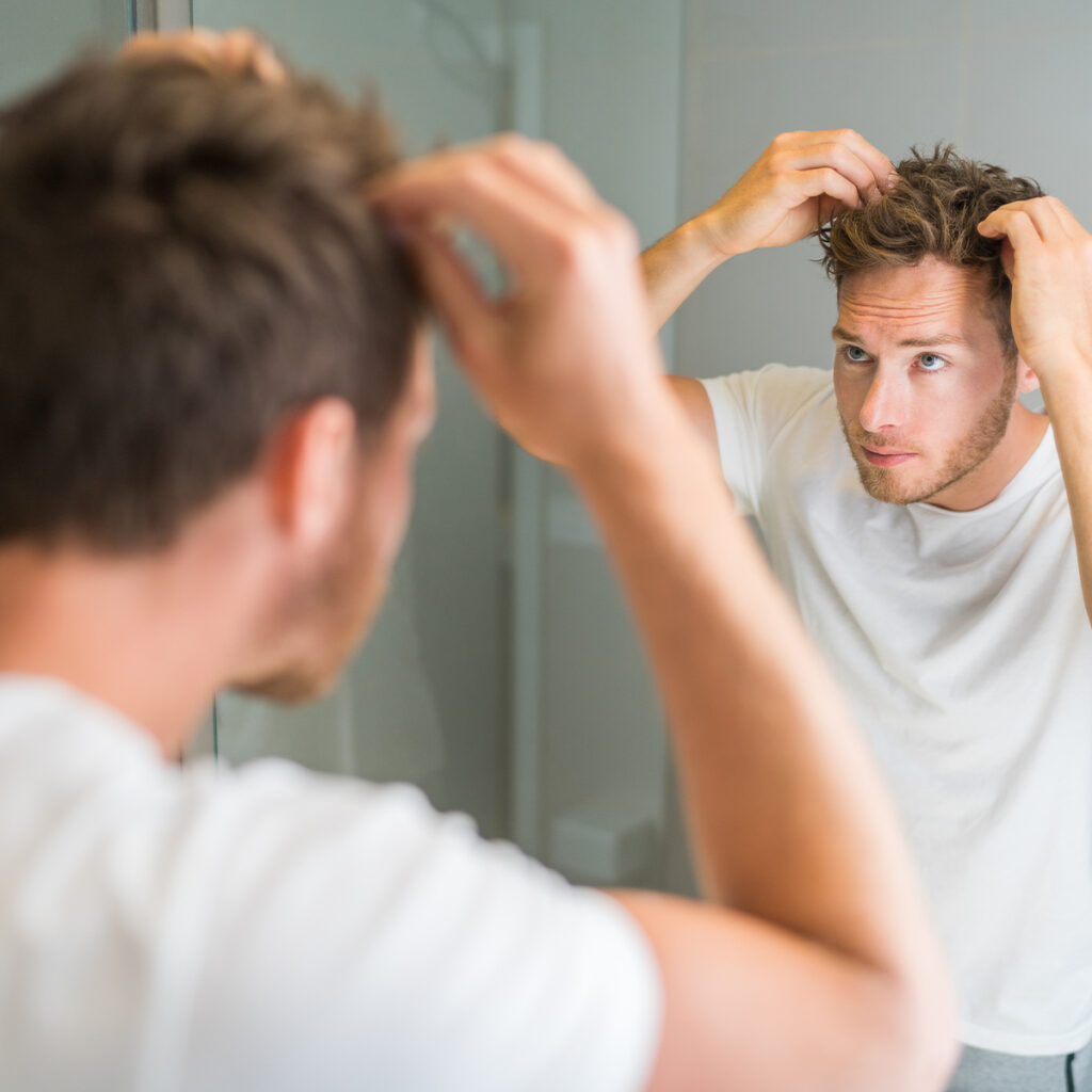 Photo of a man with a full head of hair looking in the mirror
