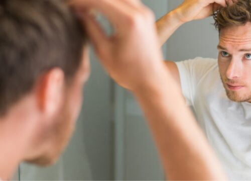 Photo of a man checking his hair in the mirror