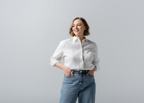 Photo of a woman wearing a white shirt and jeans against a gray background